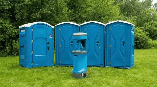 Four blue portable toilets and a matching hand washing station on grass near trees, a common sight at local outdoor events in Salt Lake City, UT